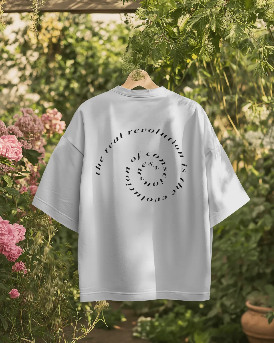 Back of the Saint White Consciousness t-shirt with the spiral text print, hanging in a garden